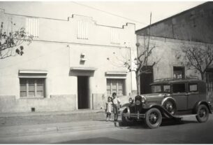 © Archivo Brügmann: En un tradicional barrio de Santiago con casas de fachada continua, dos niños posan junto a un antiguo auto Ford A, en la década de 1940.